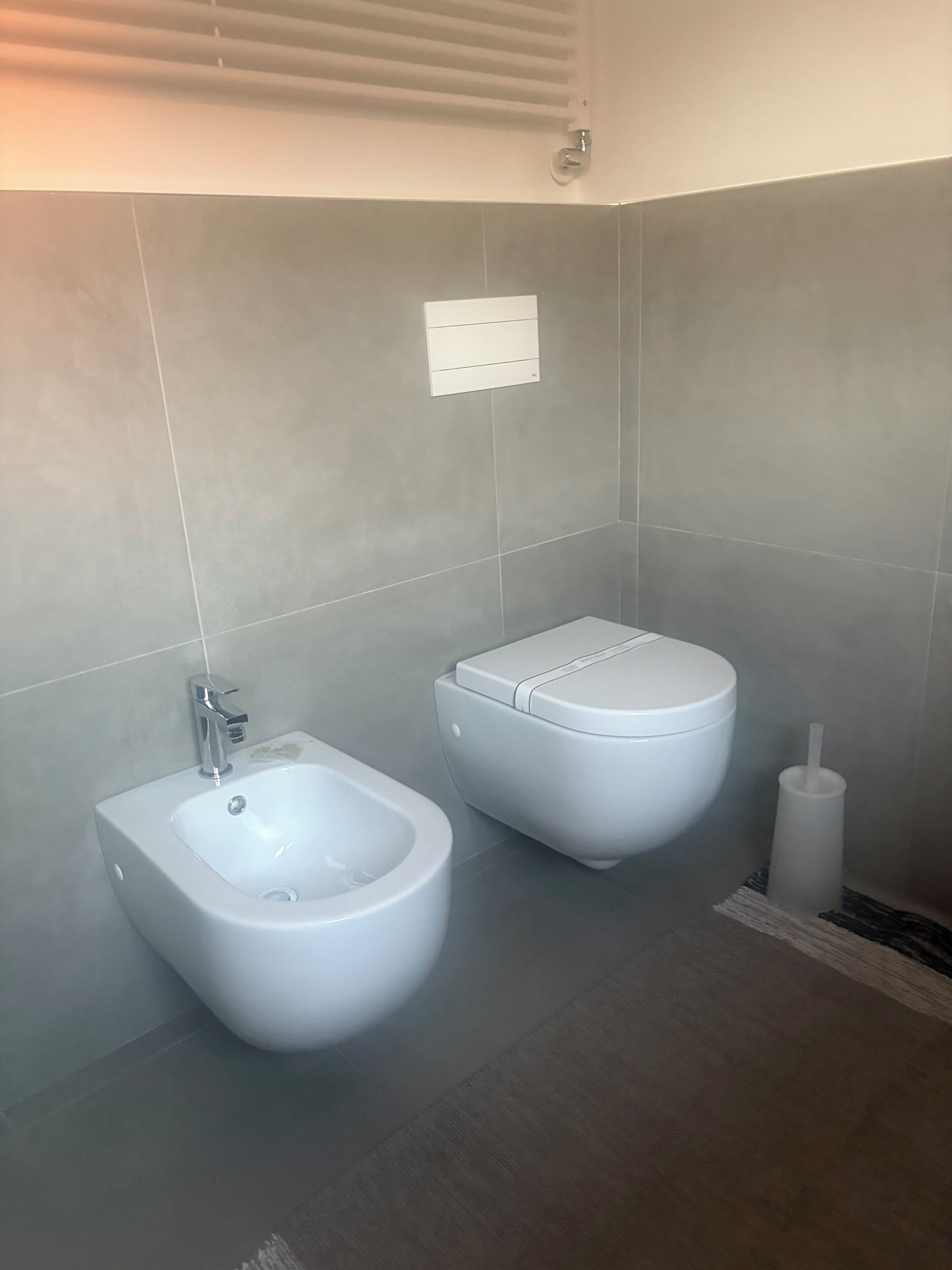 A modern bathroom with a bidet, toilet, and a hand dryer.