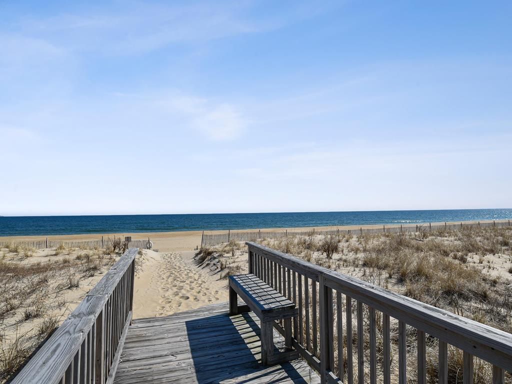 A wooden boardwalk leading to a beach with a clear sky.