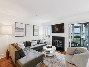 Una sala de estar moderna con sofá, sillón y chimenea.