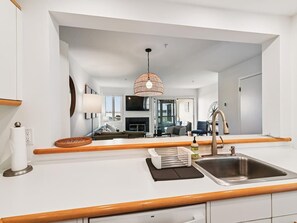 Una cocina moderna con una isla grande, un lavamanos de acero inoxidable y una lámpara colgante.