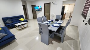 A modern living room with a blue sofa, a dining table set for four, and a TV mounted on the wall. - Central Apt, Ground Floor, 24h Secure Parking (Durango)