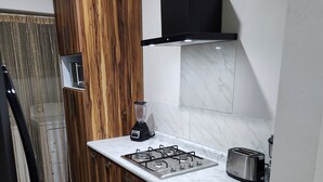 A modern kitchen with a wood finish cabinet, a gas stove, a toaster, and a blender. - Central Apt, Ground Floor, 24h Secure Parking (Durango)