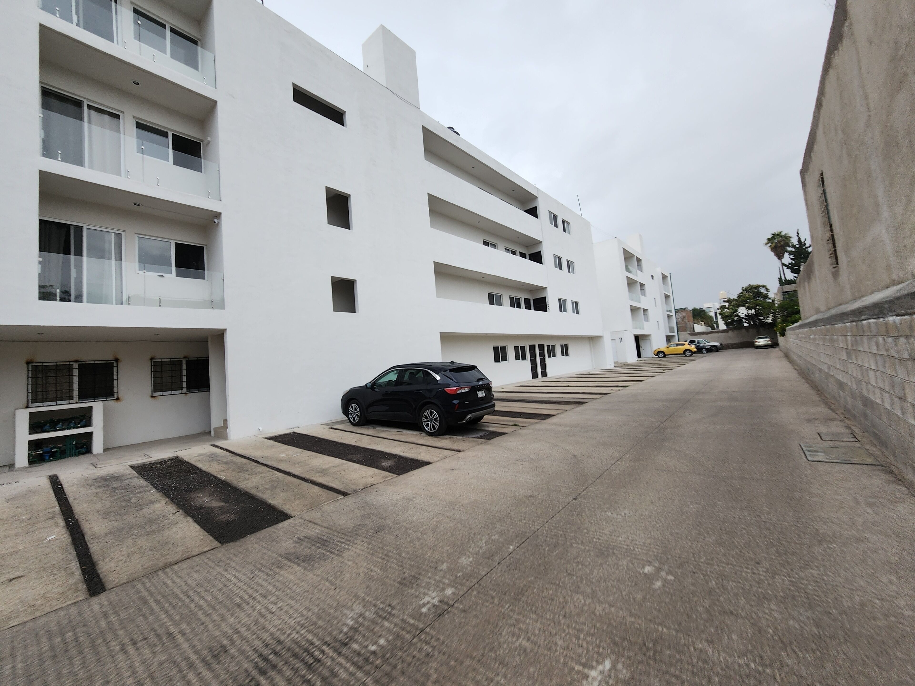 A modern multi-story residential building with a parking area.