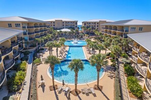 A hotel with multiple balconies, a central pool, and palm trees. - Paradise at 30A! 3 Bdrm plus bunks, sleeps 10-just 96 seconds to the beach! (Santa Rosa Beach)