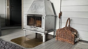A wood stove in a room with white walls and a grey floor. - Lomariihi 4 (Muurame)