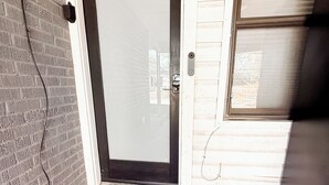 A front door with a doormat that reads "hello" and a small step leading up to the entrance.
