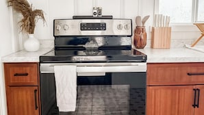A kitchen with a stainless steel oven, a microwave above it, wooden cabinets, and a window with a view.