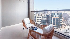 Uma varanda com móveis de vime, uma mesa de vidro e vista para a cidade.