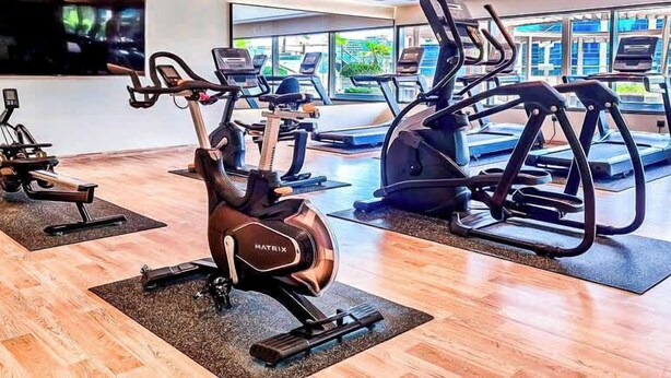 Uma academia com bicicletas ergométricas, esteiras e colchonetes.