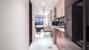 Cozinha de hotel moderna com ilha central, máquina de lavar e uma grande janela com vista para a cidade.