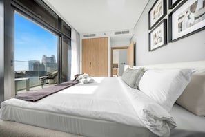 A modern hotel room with a large bed, a balcony with a city view, and a wardrobe. - Stayshort - Beautiful 1BR in Business Bay Sleeps 4 (Dubai)