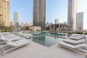 A rooftop pool with lounge chairs, surrounded by high-rise buildings. - Stayshort - Beautiful 1BR in Business Bay Sleeps 4 (Dubai)