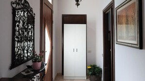 A hallway with a white wardrobe, a decorative metal piece, and a potted plant. - At Licia's house (Cuggiono)