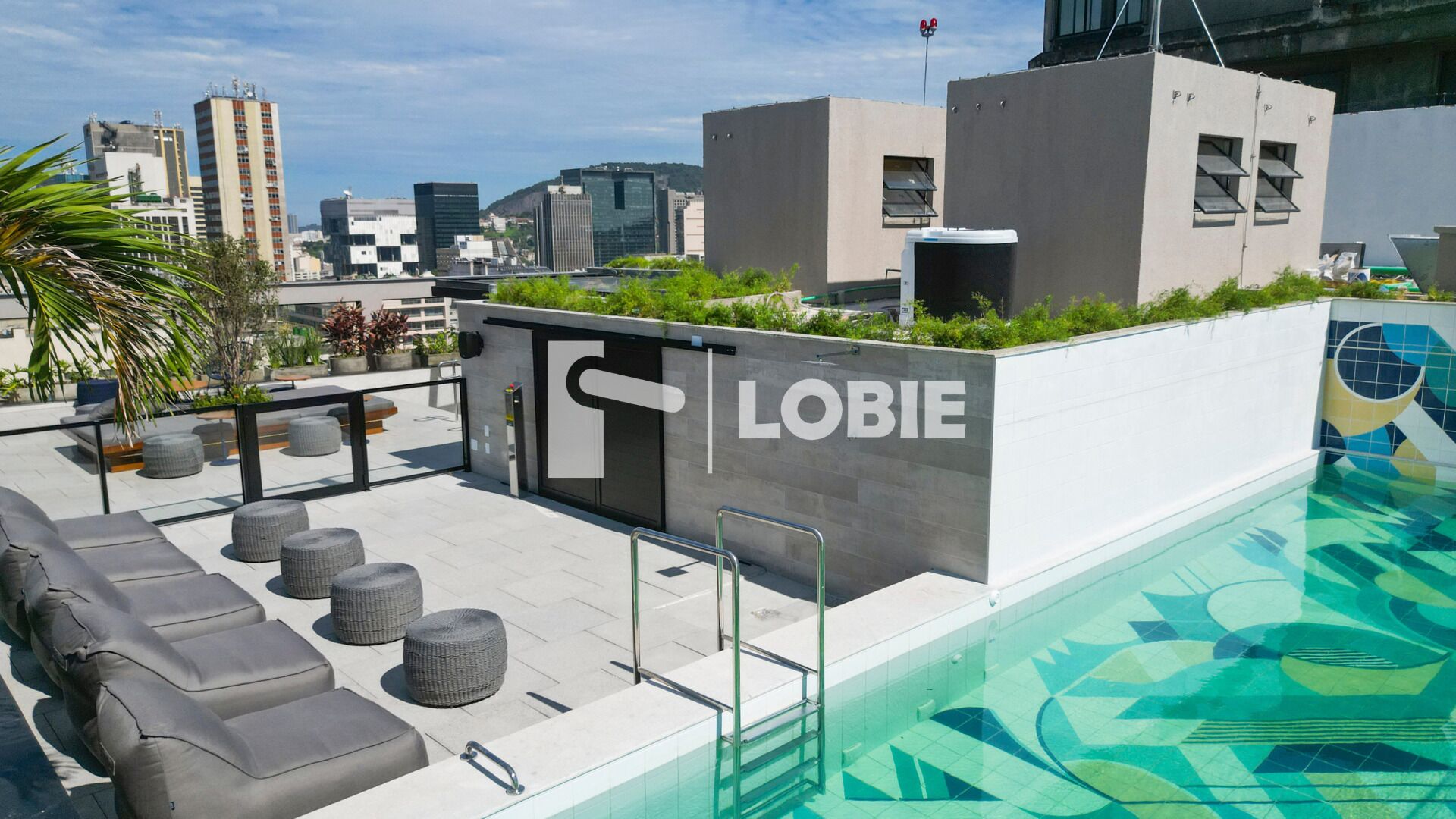 Un espace piscine sur le toit, avec des fauteuils et un panneau indiquant « LOBIE ».