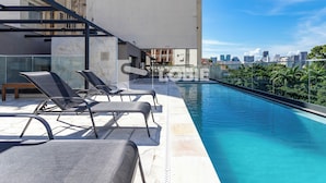 A rooftop swimming pool with lounge chairs, a city skyline view, and a modern building facade. - Lobie Glória Del'Art (Rio de Janeiro)