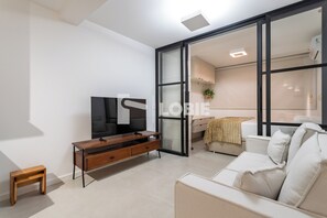 A modern living room with a flat-screen TV, wooden entertainment unit, and a white sofa. - Lobie Glória Del'Art (Rio de Janeiro)
