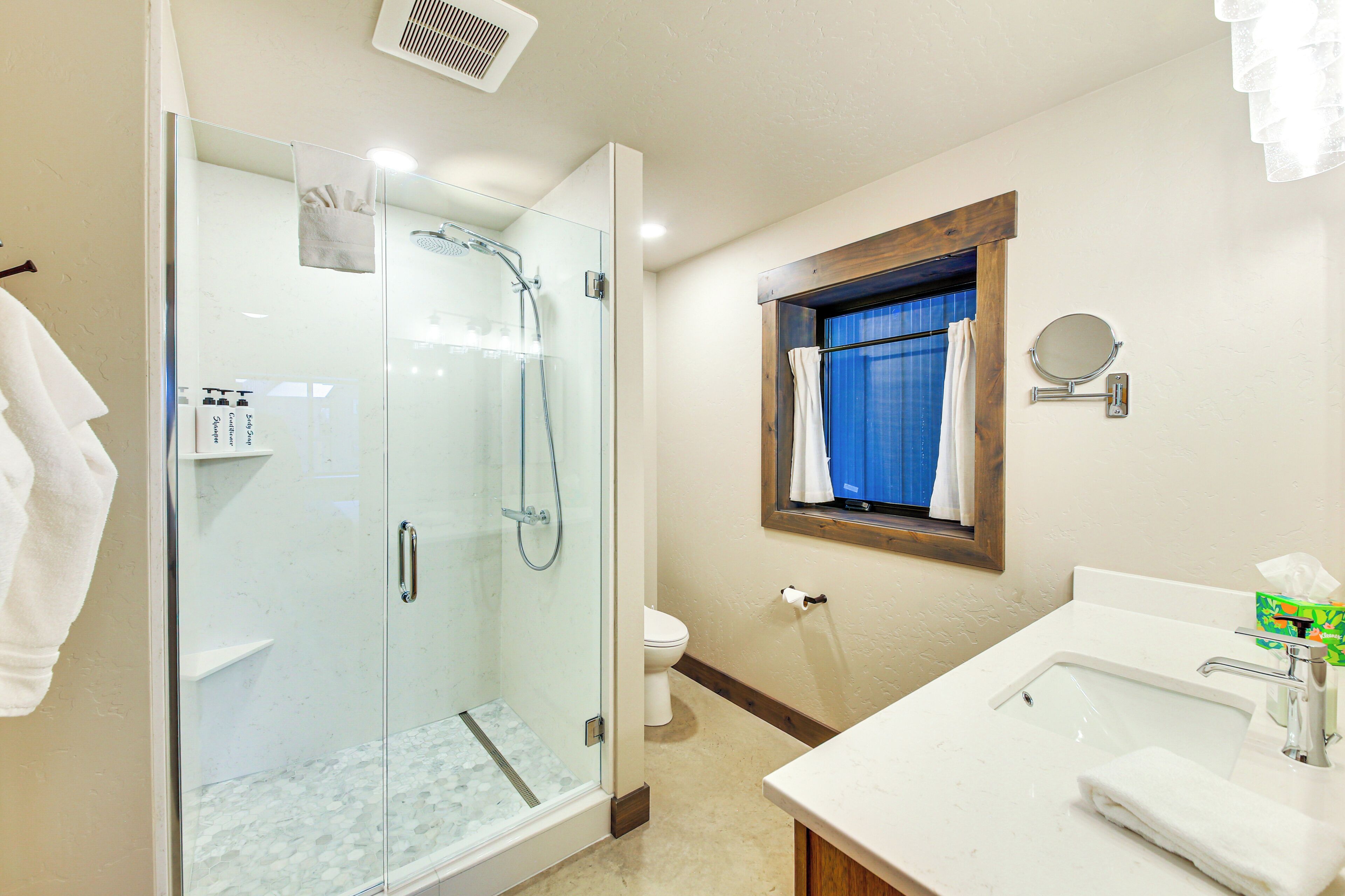 A bathroom with a glass-enclosed shower, a sink with a mirror, and a toilet.