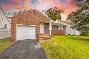 A single-story brick house with a white garage door, a front porch, and a well-maintained lawn. - Spring Getaway Hot Tub, HDTV, Game Room & Parking (Linden)