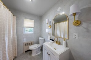 A bathroom with a toilet, sink, vanity, mirror, and towel rack. - Spring Getaway Hot Tub, HDTV, Game Room & Parking (Linden)