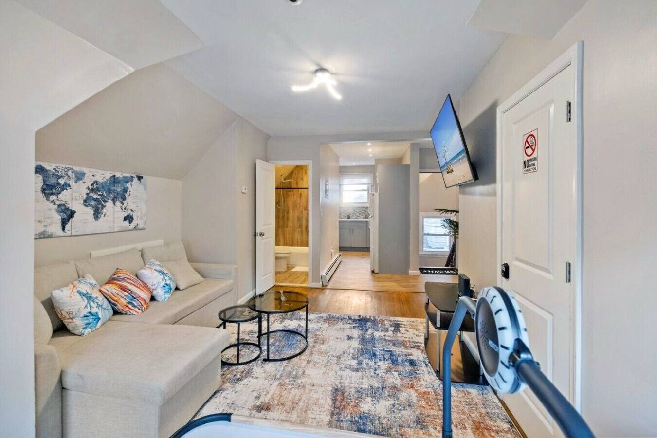 En moderne stue med sofa, sofabord, fjernsyn og et verdenskort på væggen.