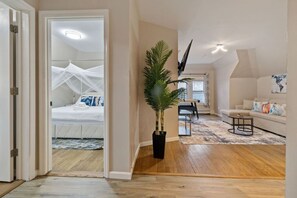 A bedroom with a canopy bed, a dining area with a table and chairs, a living room with a sofa and a coffee table, and a large potted plant.