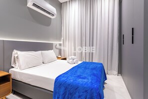 A modern hotel room with a neatly made bed, white linens, a blue throw blanket, and a large window with white curtains. - Lobie Dias Downtown (Rio de Janeiro)