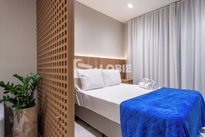 A modern hotel room with a bed, a nightstand, a potted plant, and a window with curtains. - Lobie Dias Downtown (Rio de Janeiro)