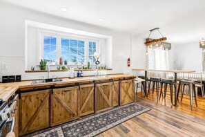 Eine moderne Küche mit einer Holztheke, einem Essbereich mit Tisch und Stühlen sowie einem großen Fenster mit Blick.