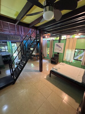 A room with a bed, a staircase, a ceiling fan, and a window with curtains. - Cabuya Lodge (Cobano)