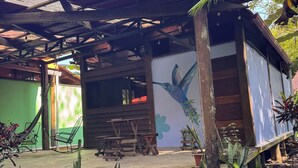 Um edifício rústico com telhado inclinado, bancos de madeira e um mural de um pássaro na parede.