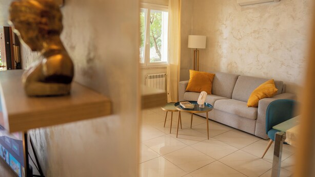 A modern living room with a sofa, a coffee table, and a lamp. - NEW Charming 2-Bedroom Apartment in Private Roman Villa Oasis (Lazio)