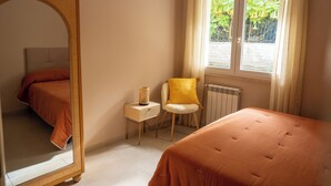 A bedroom with a large mirror, two beds, a chair, and a window with curtains. - NEW Charming 2-Bedroom Apartment in Private Roman Villa Oasis (Lazio)