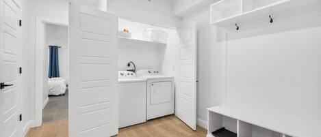 A compact laundry room with a washing machine, dryer, and a small sink.