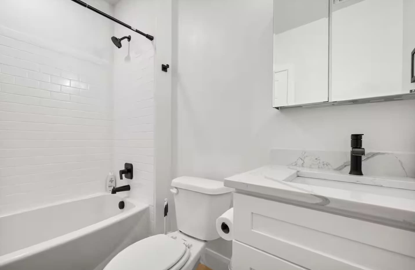 A modern bathroom with a white bathtub, toilet, and sink.