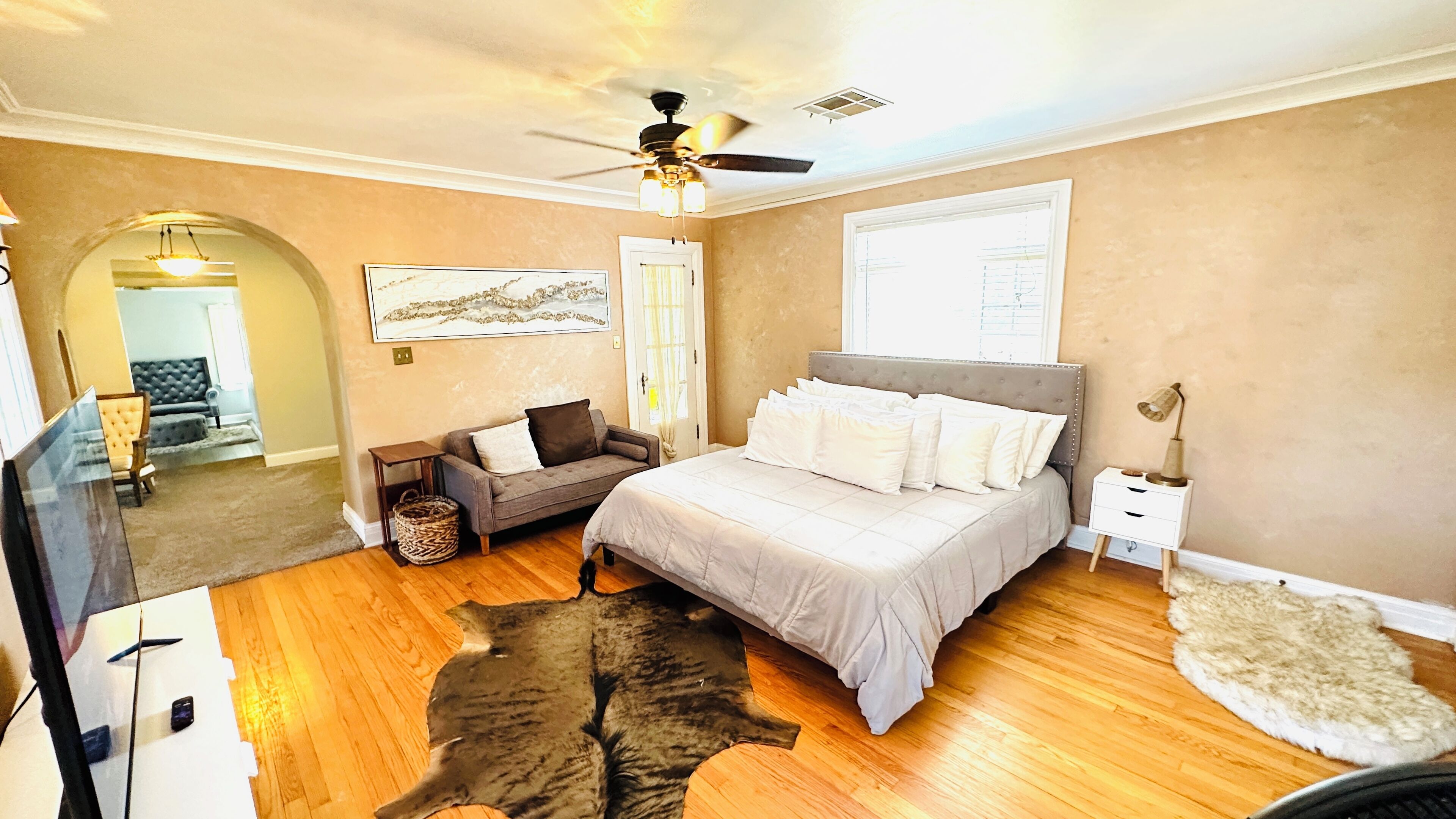 Une chambre  à coucher avec un lit, un ventilateur de plafond, un tapis et un téléviseur.