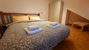 A bedroom with a large bed, a wardrobe, and a small chair. - KindStay Suite 2 bedroom Apartment w/ Free Parking near Prague Airport (Praha-Zapad)