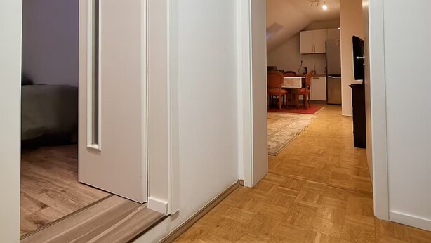 A modern interior with a wooden floor, a kitchen area with a dining set, and a bedroom with a bed and a nightstand. - KindStay Suite 2 bedroom Apartment w/ Free Parking near Prague Airport (Praha-Zapad)