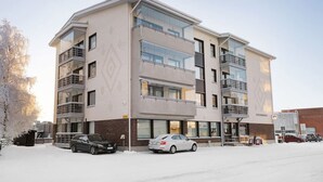 Un immeuble résidentiel à plusieurs étages, doté de balcons, d’un garage et d’un espace de stationnement.