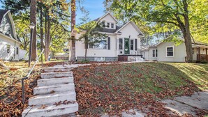 A residential house with a front yard, a concrete staircase, and a driveway.