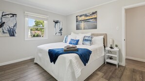 A bedroom with a large bed, a nightstand, and a window with blinds. - Two Beach Homes with 2 Hot Tubs Sleeps 20+ (Michigan City)