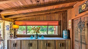 Une cuisine rustique avec des meubles en bois, une fenêtre donnant sur un paysage verdoyant et un vase décoratif posé sur le plan de travail.
