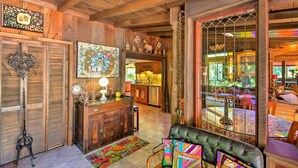 Un intérieur rustique avec des poutres en bois, un coin repas avec une table et des chaises, et un espace salon confortable avec un banc rembourré.