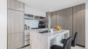 A modern kitchen with a marble island, built-in appliances, and wooden cabinetry.