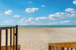 A sandy beach with a wooden fence in the foreground.