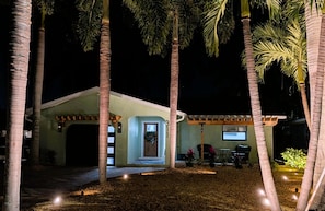 A house with a garage, a covered porch, and a well-lit entrance. - Island getaway steps from the beach with pool (Indian Rocks Beach)