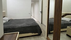 Ein modernes Schlafzimmer mit zwei Betten, einem Holzschrank und einem Spiegel.