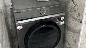 Eine Waschmaschine mit Frontlader, einem Bedienfeld, einem Wäschekorb auf der Oberseite und einem Aufkleber für eine 10-jährige Garantie.
