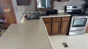 Una cocina con armarios de madera, un horno de acero inoxidable y una encimera.