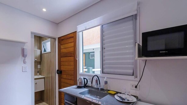 Una cocina compacta con microondas integrado, hervidor de agua y pileta.