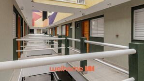 Un pasillo con varias puertas, piso de baldosas y techo con diseño geométrico.